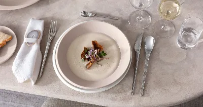 Et dekket bord med Villeroy & Boch NewMoon-tallerkener og bestikk med fløtesuppe.