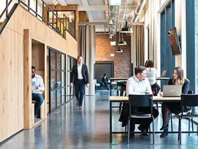 A group of people sit at desks, working or talking, in front of laptops in a modern open-plan office from Villeroy & Boch.