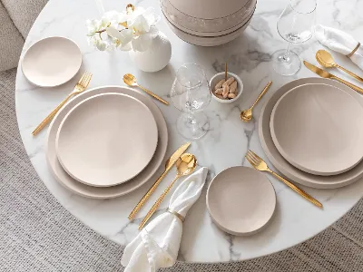 A table set with Villeroy & Boch beige NewMoon plates and gold MetroChic cutlery