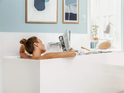 A woman relaxing in a white Subway 3.0 bath and reading a magazine.