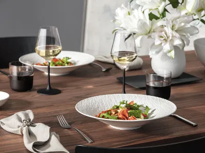 A contemporary Manufacture Rock Blanc tableware set paired with a matching Carré vase with flowers for a clean, modern table setting.