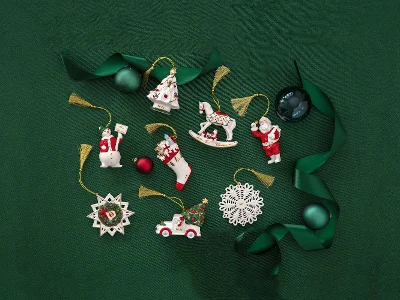 Des décorations de Noël Annual Christmas Edition 2024 avec un Père Noël, un flocon de neige et un cheval à bascule sur fond vert avec un ruban vert et des décorations en forme de boules.