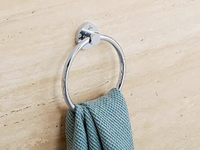 An einer beigen Marmorwand ist ein verchromter Handtuchring angebracht, der ein strukturiertes blaues Handtuch hält.