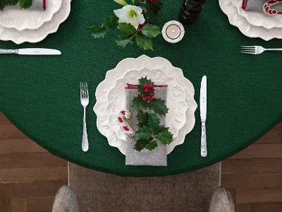 A table set for Christmas with a green tablecloth, white plates decorated with holly from Villeroy & Boch’s Toy’s Delight Royal Classic collection, a candy cane, a sprig of holly on the napkin, and silver flatware.