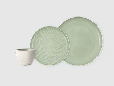 Eine weiße Tasse, ein strukturierter hellgrüner Teller und ein glatter hellgrüner Essteller sind nebeneinander angeordnet.