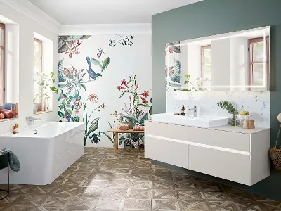 A Collaro washbasin, furniture and bath in a bathroom with floral wallpaper.