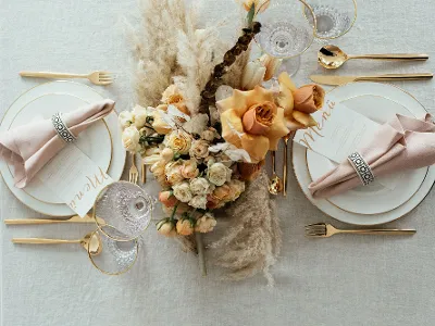 Elegant table decoration with gold MetroChic cutlery, Anmut crockery with a gold rim, a floral centrepiece and menu cards.