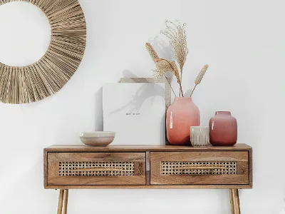 A wooden console table with Perlemor vases and a round mirror.