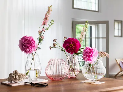 Four different vases from the Villeroy & Boch Rose Garden collection standing on a wooden table.