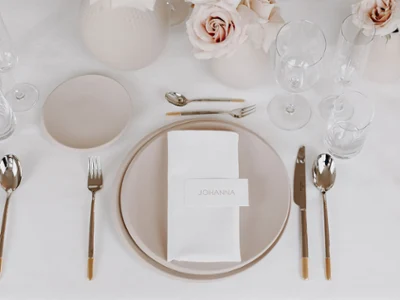 A festively set table with white and beige NewMoon plates, Ella flatware and NewMoon glasses.