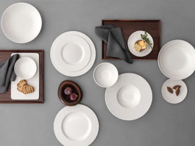 A formal table setting with a Manufacture plates A formal table setting with a white bowls and plates on a grey table and food on it.