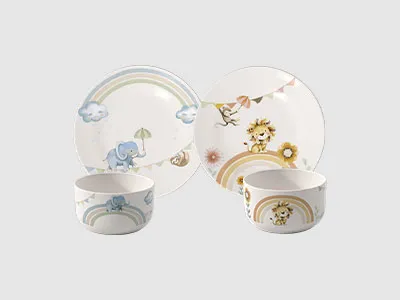 Zwei Kindergeschirrsets mit Schüsseln und Tellern mit Regenbögen, Tieren und Pastellmotiven auf hellem Hintergrund.