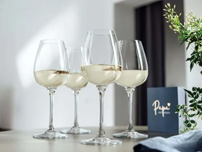 Trzy kieliszki do białego wina z kolekcji Purismo na stole z kartką z życzeniami w tle.