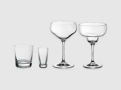 Vier Arten von leerem Glas: ein Whiskyglas, ein Schnapsglas, ein Coupe-Glas und ein Margarita-Glas auf schlichtem Hintergrund.