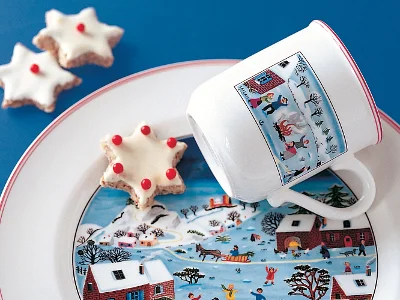 Tasse de Noël au design naïf posée sur une assiette avec un biscuit en forme d'étoile.