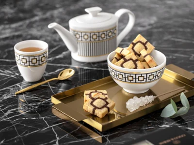 Elegant MetroChic tea set with a teapot and a cup Elegant MetroChic tea set with a teapot and a cup on a gold tray, on a marble table.