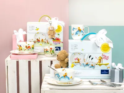 Happy as a Bear and Hungry as a Bear children’s gift items and crockery sets on a table against a pastel-coloured background.