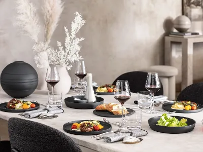 A dining table with a black La Boule being used with food as well as an assembled La Boule as decoration.