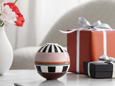 La petite Boule Memphis from Villeroy & Boch and two wrapped gifts stand on a marble table, with a vase of flowers in the background.
