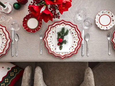 Odświętnie nakryty stół z talerzami, sztućcami i szklankami Toy's Delight, starannie ułożonymi na beżowym obrusie.