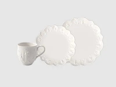 Eine weiße Keramiktasse und zwei gewellte weiße Teller sind vor einem schlichten hellen Hintergrund angeordnet.