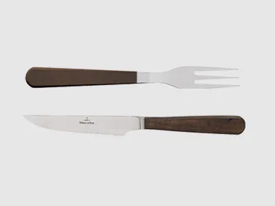 Ein Steakmesser und eine Fleischgabel mit Holzgriffen, nebeneinander auf einem schlichten Hintergrund platziert.