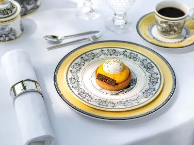 A small dessert with yellow topping and whipped cream on a decorative plate from the Audun collection by Villeroy & Boch. 
