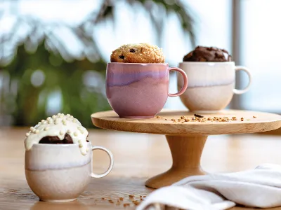 Three Perlemor mugs filled with mug cake on a wooden stand.