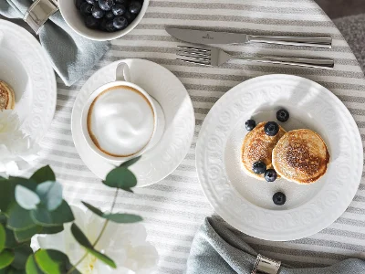 Service de table avec la collection Cellini de Villeroy & Boch, comprenant une tasse à café, des crêpes aux myrtilles et des couverts.