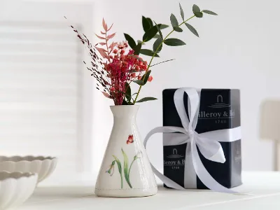 Frühlingshafte, kleine Colourful Spring Vase mit Blumen vor einer Villeroy & Boch Geschenkverpackung.