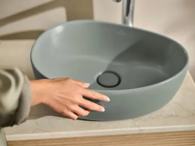 A hand touching a freestanding washbasin from the Antao bathroom collection by Villeroy & Boch.