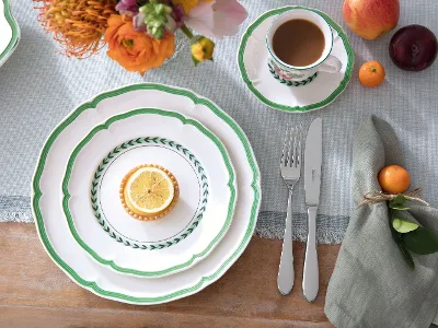 A rustic table setting with French Garden plates, a delicious lemon dessert, a cup of coffee and fresh flowers.