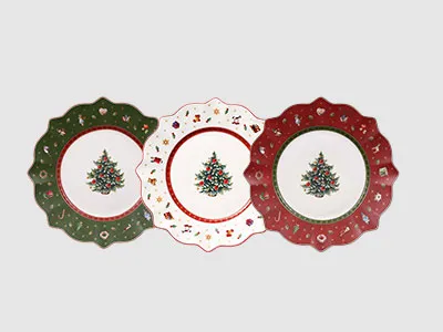 Drei dekorative Teller mit Weihnachtsbaummotiven und grünen, weißen und roten Wellenrändern, nebeneinander ausgestellt.