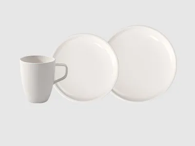 Vor einem schlichten hellen Hintergrund sind eine weiße Keramiktasse und zwei weiße Essteller zu sehen.