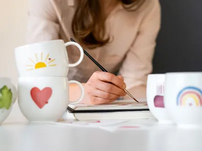 With Love cups with different motifs while a woman paints in the background.	