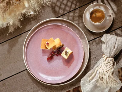 A pink like. by Villeroy & Boch Perlemor breakfast plate with a piece of cheese and a cup of coffee.