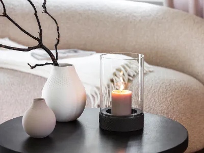 A Manufacture candle standing on a table next to two Manufacture vases.