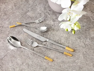 Elegant Ella cutlery set with gold details on a marble table top, together with a white orchid.