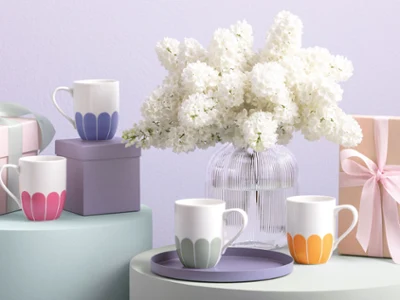 Villeroy & Boch Fleur cups in pastel colors, a Fleur vase, gift boxes, and a white flower vase on softly toned surfaces.