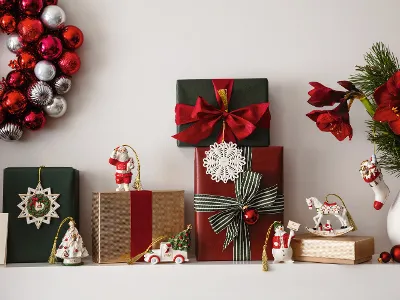 Festive Christmas shelf with wrapped presents, Christmas decorations from Villeroy & Boch, a wreath with red and silver ornaments from Villeroy & Boch, and a vase with red flowers and green plants.