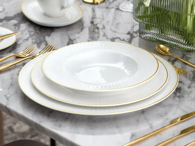 Un service de table formel avec des assiettes blanches, des couverts en or, une saucière blanche et une composition florale sur une table en marbre.