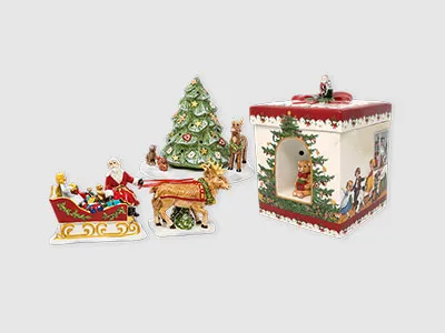 Verschiedene Weihnachtsdekorationen aus Keramik, darunter ein Baum, ein Schlitten, ein Rentier, Figuren und eine festliche Schachtel auf grauem Hintergrund.