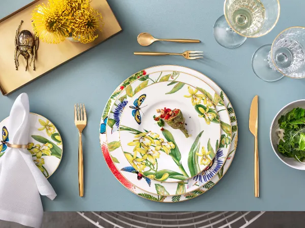 Elegant dining table with an Amazonia Anmut plate, MetroChic cutlery in gold, crystal glasses and a beetle figurine.