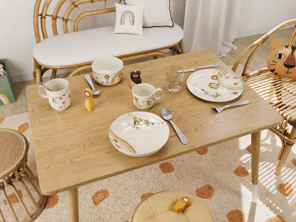 De la vaisselle pour enfants Boho Kids Roar like a lion sur une table en bois dans une salle à manger confortable Une salle à manger confortable avec une table en bois, des chaises en osier et de la vaisselle colorée pour enfants Boho Kids Roar like a lion.