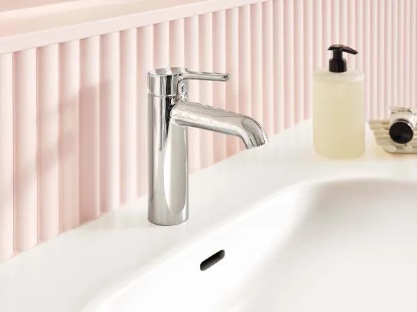 Chrome Waschbecken-Armatur in einem soften, runden Design aus der Skyla Badkollektion in Kombination mit dem Skyla Waschtisch - beide in einer pastellfarbigen Umgebung in Rosatöne.