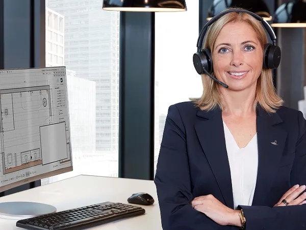 Villeroy & Boch employees working at desks in an open-plan office, one employee giving advice on a video call.