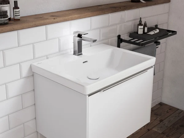 Bateria umywalkowa Subway 3.0 z białymi płytkami Strefa umywalki przy ścianie wyłożonej białymi kafelkami z ciemną drewnianą półką i drewnianą podłogą