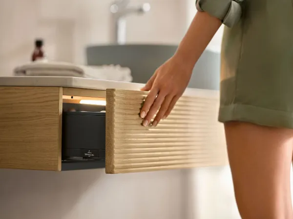 A woman in a bathroom opening a console drawer in the Antao bathroom furniture collection by Villeroy & Boch.