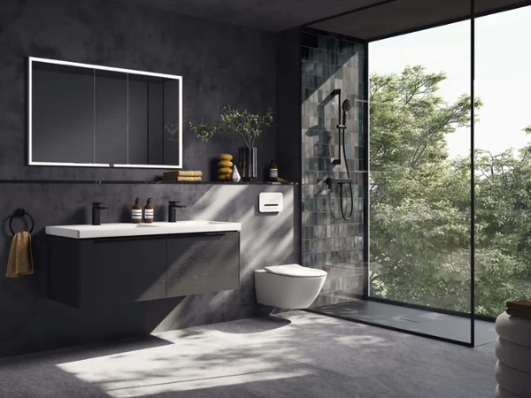 All-black style sloping ceiling bathroom Modern bathroom with dark wall tiles, an illuminated square More to See Lite mirror, a black Loop & Friends surface-mounted washbasin on a floating Antao washstand and a towel holder with a pink towel, all in soft daylight.