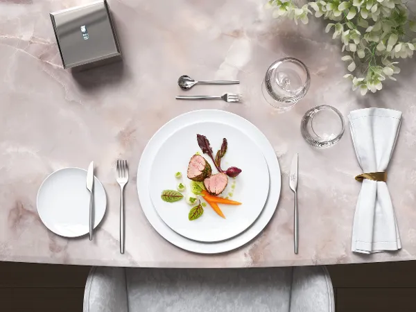 Stylish marble table with gourmet food on white MetroChic plates, together with MetroChic cutlery and floral decorations.